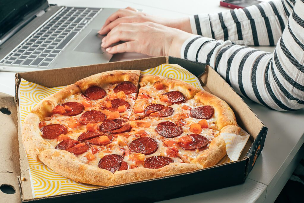 woman using laptop-and eating pizza concept of food ordering